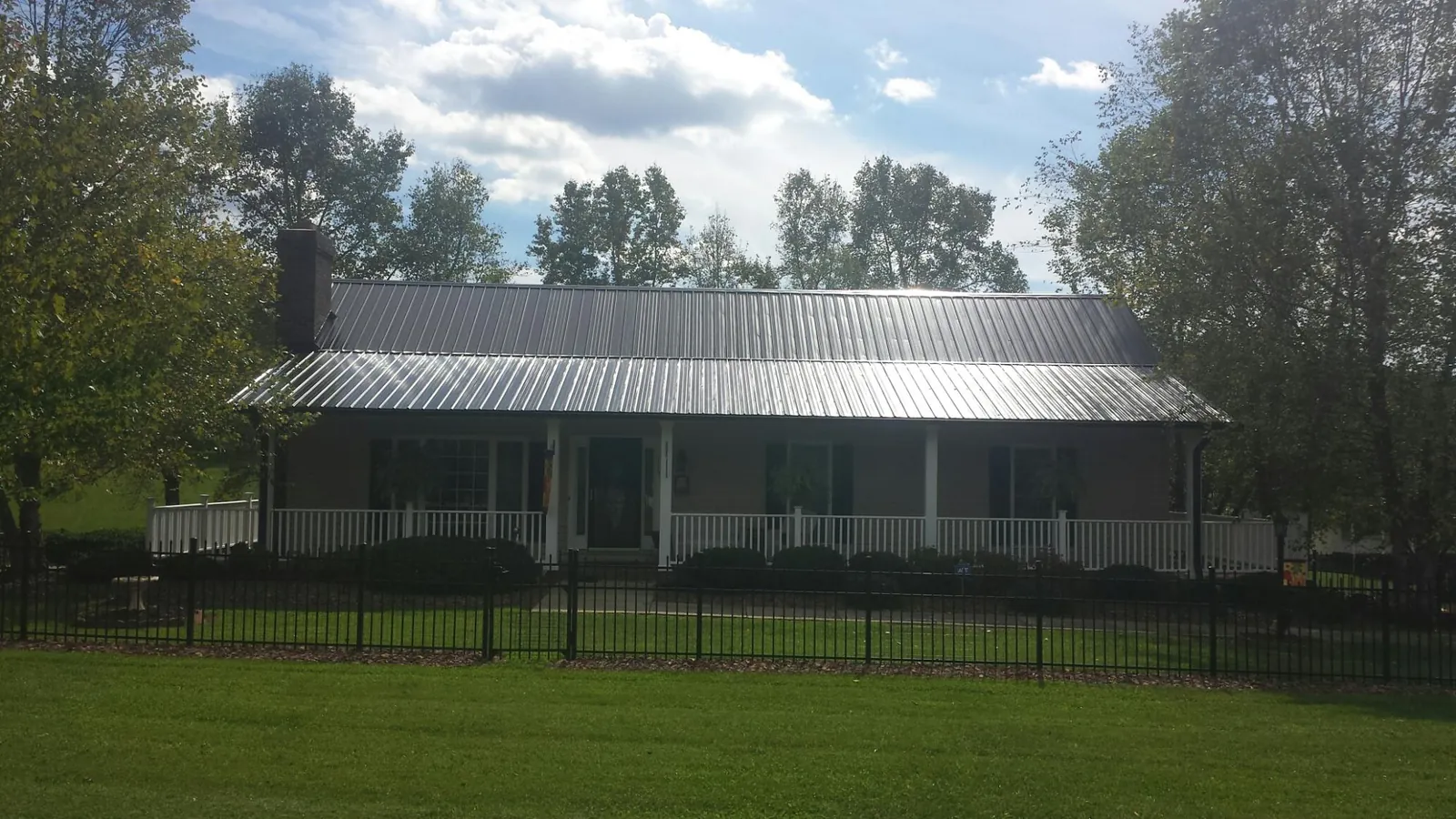 Gray metal roof on a brick ranch with a full width front porch — Gutter Guard Installation work by our crew in Baker